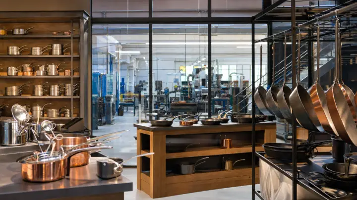 Poêles et ustensiles de cuisine exposés devant un atelier métallurgique